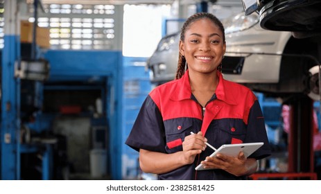 Happy Black female supervisor mechanic, cheerful smile, inspects repair work checklists with tablet at garage, service car maintenance, and fixing specialist occupations in auto transport industry. - Powered by Shutterstock