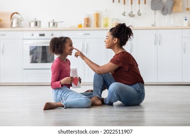 Happy Black Girl Greeting Her Mom With Mothers Day, Giving Handcraft Card, Sitting On Floor At Kitchen And Smiling At Each Other, Emotional Mummy Touching Her Teen Kid Nose, Mothers Day Celebration