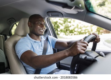 Happy Black Guy In Casual Driver Enjoying Driving His New Auto, Holding Hands On Steering Wheel, Fasten With Seat Belt, Looking At Road And Smiling, Shot From Dashboard, Copy Space