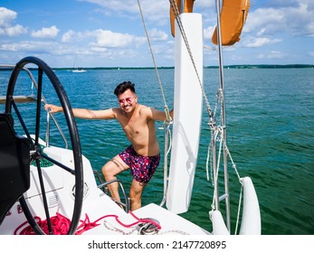Happy black hair man down the ladder into the water. A man down into the water on an iron ladder on the sailing yacht a to swim