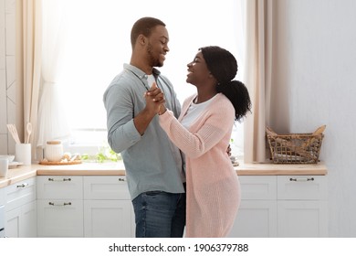 Happy Black Husband And Wife Dancing In Kitchen Interior, Romantic African American Spouses Looking At Each Other And Smiling, Loving Couple Having Fun And Enjoying Spending Time At Home, Copy Space - Powered by Shutterstock