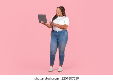 Happy Black Lady Using Laptop Computer Working Online Posing Standing In Studio Over Pink Background. Internet Technology, Successful Freelance Career Concept