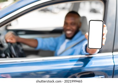 Happy Black Male Driver Holding Smartphone With Blank Screen In Hand, Mockup. Closeup Of Mobile Phone With White Empty Display, Guy Using Mobile App For Navigation, Copy Space, Selective Focus