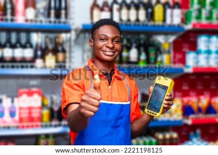 happy black male shop attendant smiling giving thumbs for approval whilst holding terminal machine