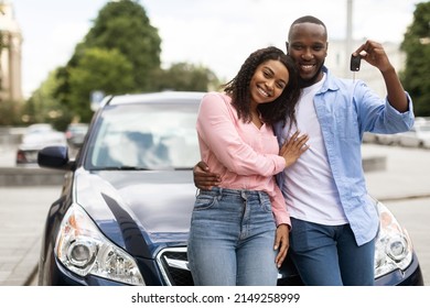 Happy Black Man Showing Keys Of Luxuy Automobile, Wife Embracing Her Husband, Young Family Using Auto Rental Service, Couple Buying New Car In Dealership Center Leaning On Vehicle, Posing At Camera - Shutterstock ID 2149258999