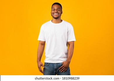 Happy Black Man Smiling To Camera Posing Standing Over Yellow Background, Studio Shot. Good Mood Concept