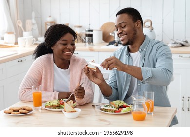 Happy Black Man Spreading Butter To Toast While Having Breakfast With Wife At Home, Happy African American Couple Sitting At Table In Kitchen And Eating Tasty Food, Enjoying Morning Together, Closeup - Powered by Shutterstock