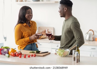 Happy Black Man And Woman Drinking Wine And Chatting While Preparing Food In Kitchen, Cheerful Young African American Couple Cooking Healthy Lunch And Relaxing Together At Home, Closeup Shot