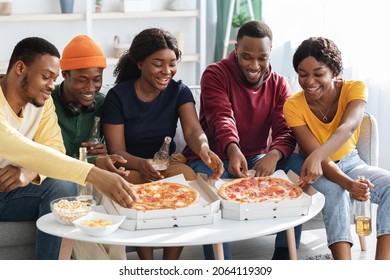 Happy Black Millennials Enjoying Pizza And Drinking Beer At Home, Sitting On Couch In Living Room, Having Conversation And Laughing, African American Friends Spending Time Together