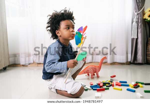 Happy black people African American child play wood\
windmill toy at home 
