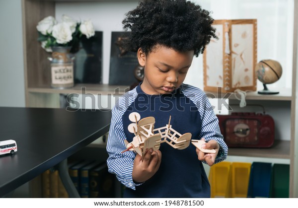 Happy black people African American child play\
paper air plane toy at home\
