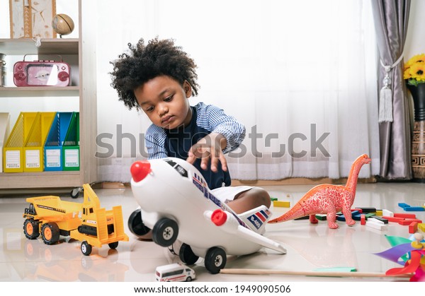 Happy black people African American child play\
truck and air plane toy at home\
