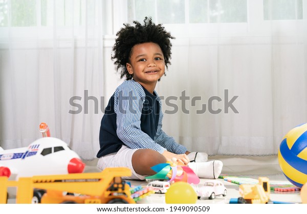 Happy black people\
African American child look at camera and smile with truck and air\
plane toy at home 