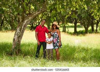 Happy Black People In Park. African American Family With Young Mom, Dad And Son Having Fun With Football. Portrait Of Man, Woman And Boy With Soccer Ball.