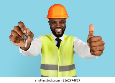 Happy Black Property Developer Wearing Hardhat Showing Home Keys And Thumb Up At Camera, Cheerful African American Civil Engineer Recommending Building And Repair Services, Blue Background, Closeup - Powered by Shutterstock