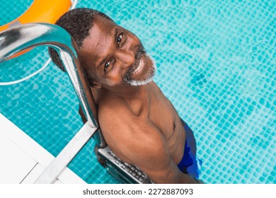 Happy black senior man having party in the swimming pool - Active elderly male person sunbathing and relaxing in a private pool during summertime - Powered by Shutterstock