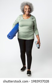 Happy black senior woman with a yoga mat and a water bottle
