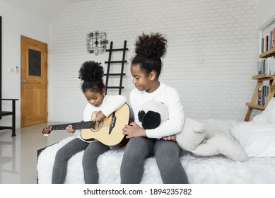 Happy Black Skin Girl Kid Play Guitar With Sister In Bed Room