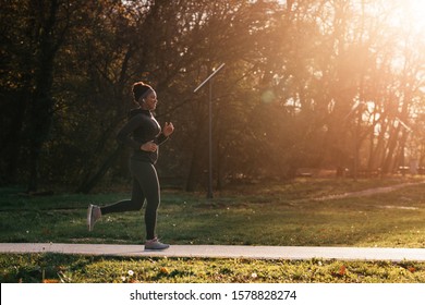 Happy Black Sportswoman Running During Sunny Day In Autumn Park. Copy Space. 