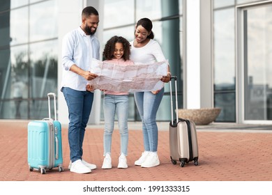 Happy Black Tourists Standing Near Airport, Checking City Map, Cheerful African American Man, Woman And Girl Planning Trip Route. Positive Family Enjoying Travelling Together, Free Space - Shutterstock ID 1991333315