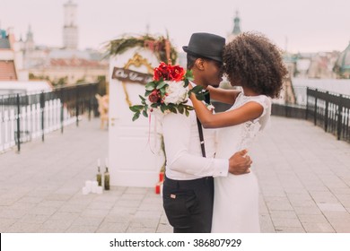 Happy black wedding couple softly hugging on the rooftop during the wedding ceremony