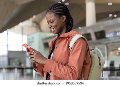 Happy Black Woman Check Message On Smartphone After Arrival Of First Flight After Covid End In Airport. Cheerful African Female Use Mobile Phone, Traveler In Terminal Happy To Travel In New Normality