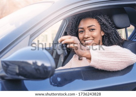 Happy black woman driving her new car holding key
