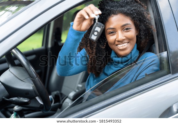 Happy\
black woman driving her new car holding car\
key