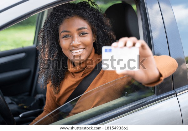 Happy\
black woman driving her new car holding car\
license