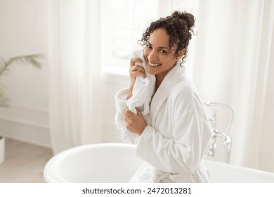 Happy black woman drying face with soft towel after bathing in the morning, lady caring for skin and smiling. Skincare and beauty routine concept - Powered by Shutterstock