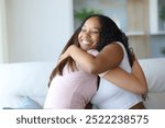 Happy black woman hugging her friend or couple on a sofa at home