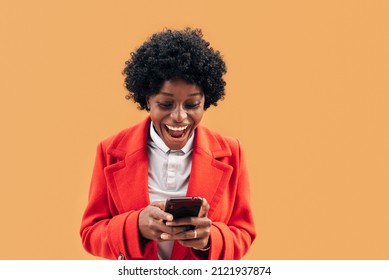 Happy black woman looking excitedly at her mobile phone while using it outdoors. Technology concept. - Shutterstock ID 2121937874