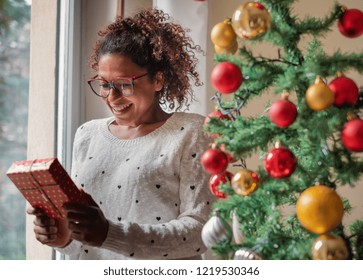 Happy Black Woman Opening Christmas Presents At Home