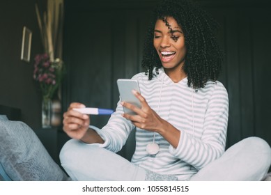 Happy Black Woman With A Pregnancy Test On Bed