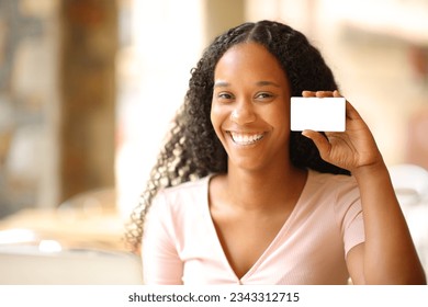 Happy black woman showing blank credit card in a bar terrace - Powered by Shutterstock