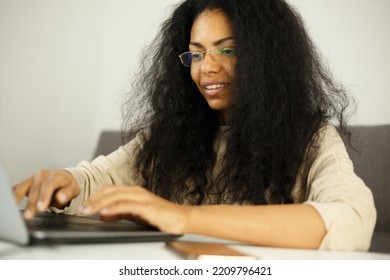 Happy Black Woman Typing Text On Computer. Cheerful Dark Skinned Female Working On Laptop At Home. Download Royalty Free Image Of African Entrepreneur Person Doung Work. Stock Photo Of Freelancer