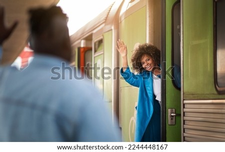 Happy Black Woman Waving Hand To Boyfriend While Standing In Train Door At Railway Station, Joyful Beautiful African American Female Greeting Her Spouse After Arrival Or Saying Bye Before Leaving