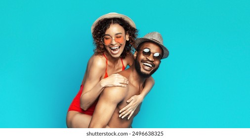 A happy black young couple is enjoying themselves while posing for a photo. The woman is wearing a red bathing suit and a straw hat, while the man is shirtless and wearing a straw hat and sunglasses. - Powered by Shutterstock