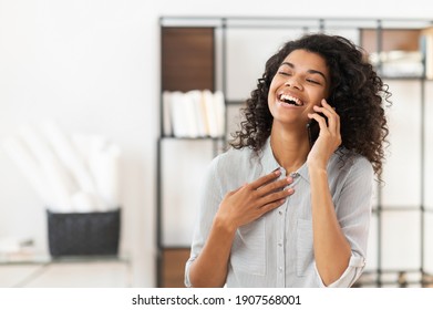 Happy blessed African American teenage girl with curly hair talking on mobile phone and laughing, expressing positive emotions, or a young joyful businesswoman is having a pleasant conversation - Powered by Shutterstock