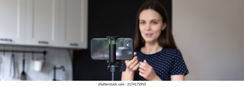 Happy Blogger Girl Giving Review For Product, Recording Video For Blog Audience, Speaking At Smartphone Webcam In Home Kitchen. Mobile Phone Fixed On Tripod Close Up. Banner Shot