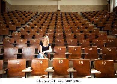 Happy blond college student alone in large lecture hall