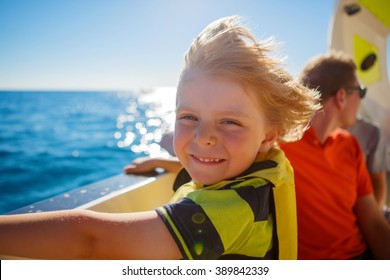 Happy Blond Little Kid Boy Enjoying Sailing Boat Trip. Family Vacations On Ocean Or Sea On Sunny Day. Child Smiling.