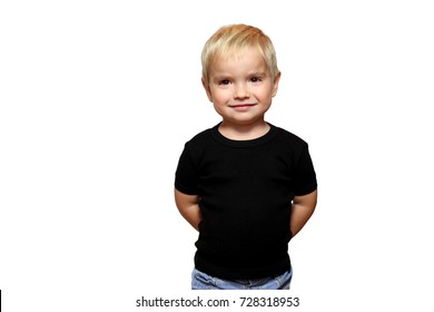 Happy Blond Toddler Boy In Black T-shirt Without Any Logo Over White Background, Hands Behind The Back, Isolated, Emotional Child Portrait, Closeup Indoor, Place For Your Text