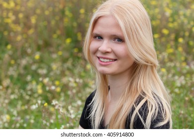Happy blonde girl in the field surrounded by flowers - Shutterstock ID 405914800