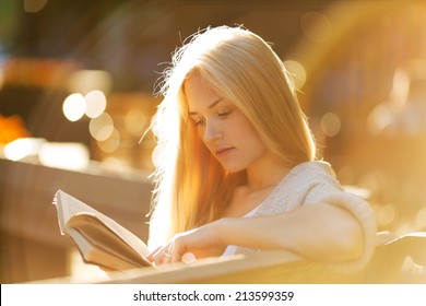 Happy blonde girl sitting and reading a book - Powered by Shutterstock