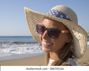 happy blonde girl smiling portrait in the beach  wearing hat and sunglasses, summer holidays