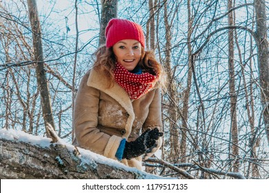 Happy Blonde Girl In Warm Clothes Inside Snowy Winter Forest With Sunset Light