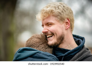 Happy blonde man living with HIV hugging his friend outside at a park in Hamburg, Germany