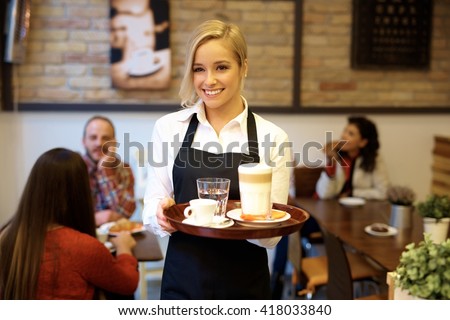Happy blonde waitress holding tray, smiling.