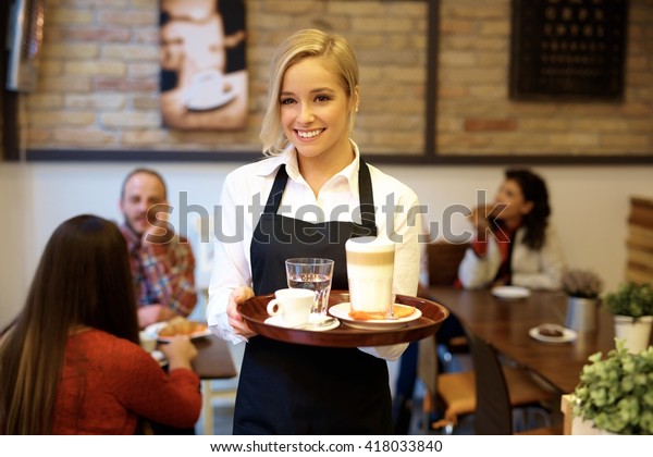 Happy blonde\
waitress holding tray,\
smiling.